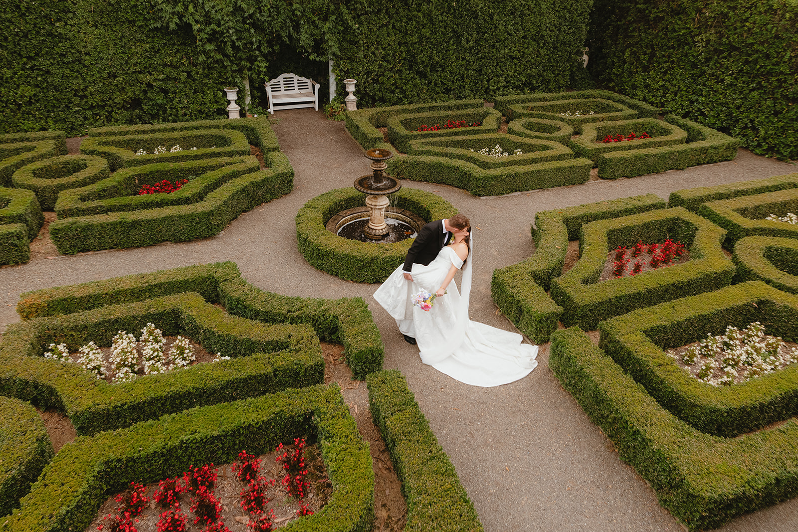 Zoe & Byron doing a dip kiss in the maze at villa candotti while being photography by lysanah maguire photography