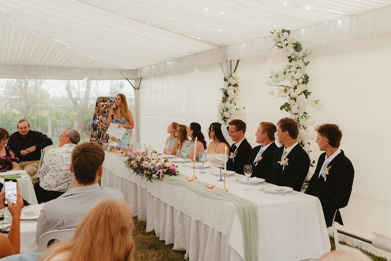 Zoe and Byron seated with guests during their wedding reception.